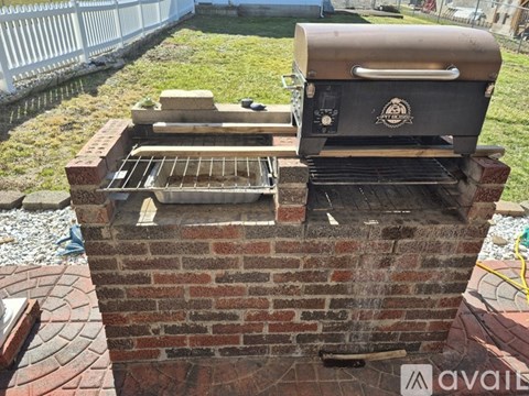 A BBQ grill is on top of a brick chimney.