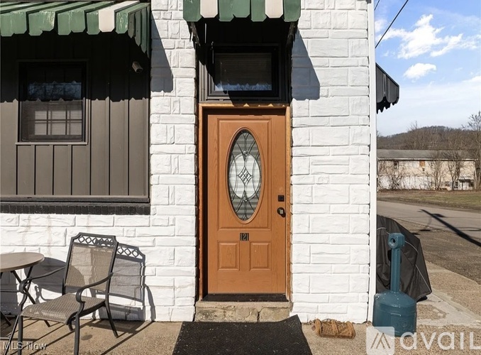 A white house with a brown door and a green awning.