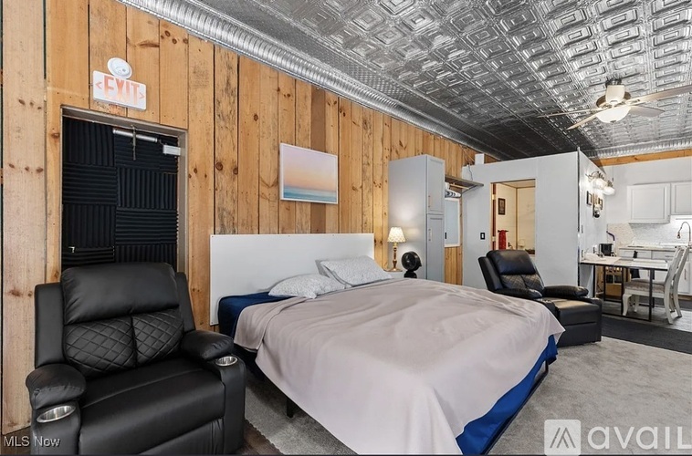 A bedroom with a bed, chair, and a poster on the wall.