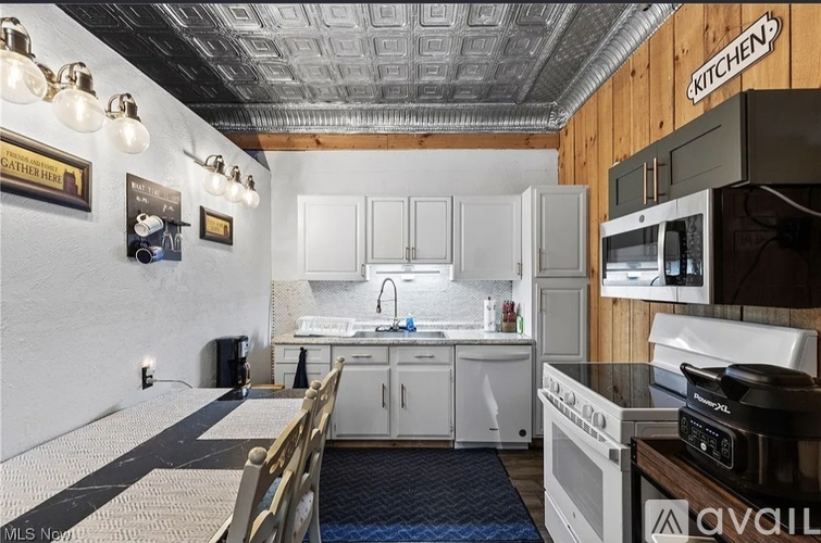 A kitchen with a white stove top oven and white cabinets.