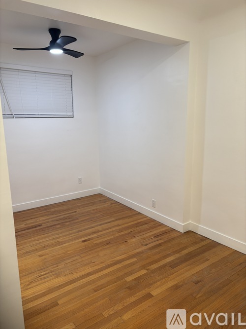 A room with a ceiling fan and wooden flooring.
