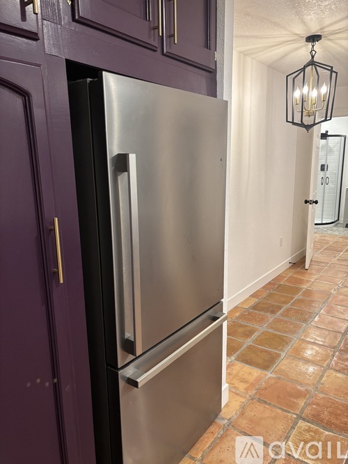 A stainless steel refrigerator in a kitchen with purple cabinets.