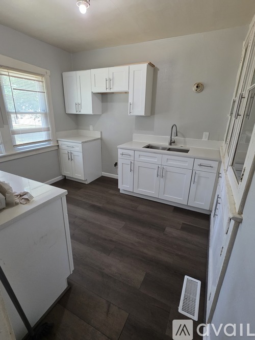 A kitchen with white cabinets and a wooden floor.