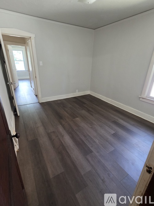 A room with wooden flooring and a doorway leading to another room.