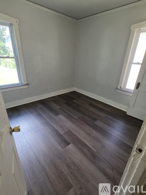A room with wooden flooring and white walls.