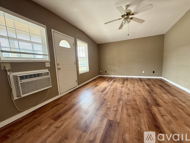 A room with a ceiling fan and wooden flooring.