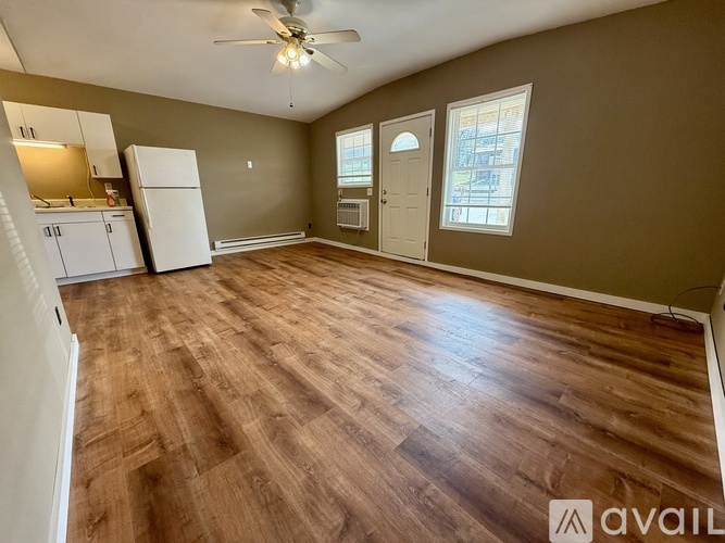 A spacious room with a ceiling fan and wooden flooring.