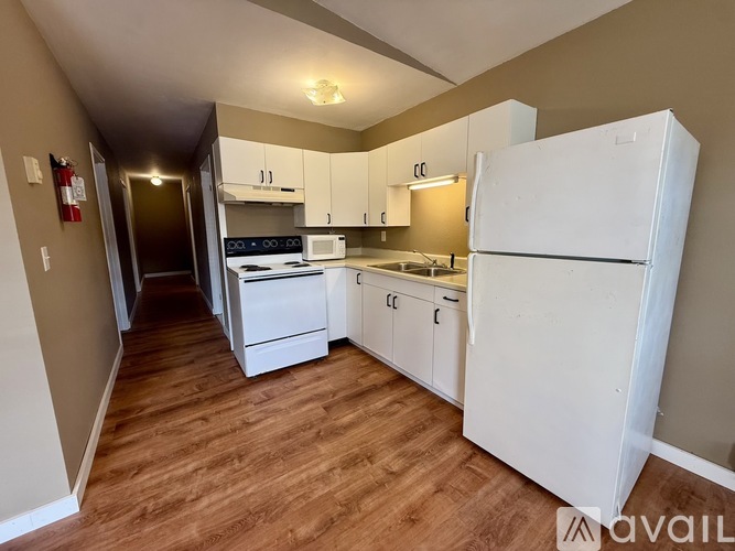 A kitchen with white appliances and wooden floors.