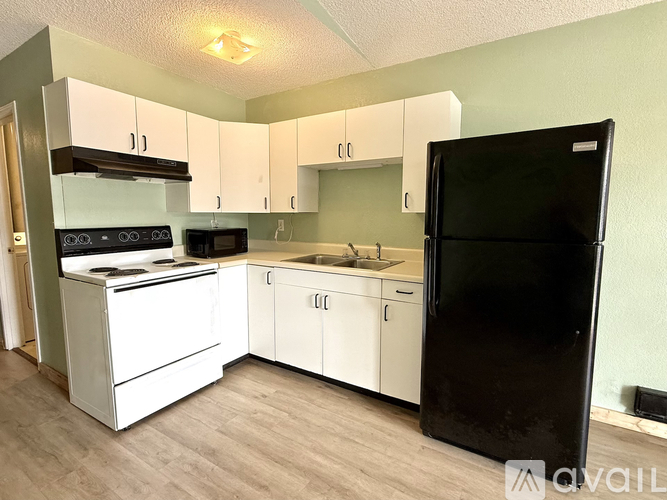 A kitchen with white cabinets and a black refrigerator.
