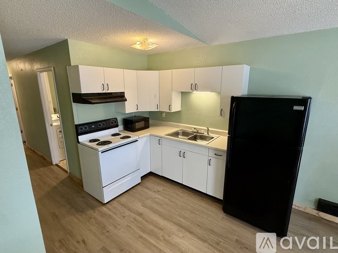 A kitchen with white cabinets and a black refrigerator.