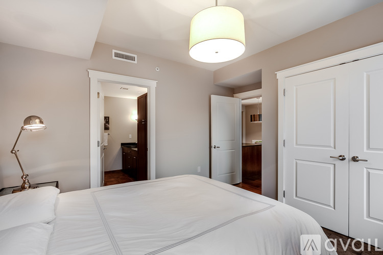 A bedroom with a large bed and a lamp on the side table.