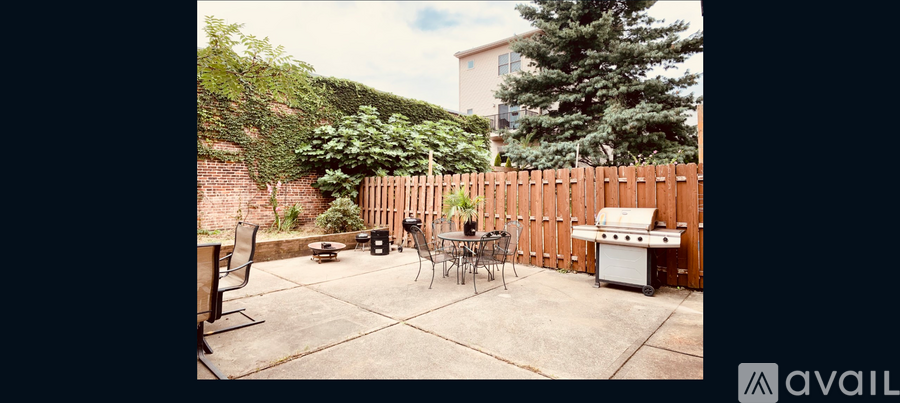 A patio with a table and chairs and a grill.