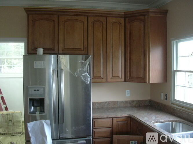 A kitchen with wooden cabinets and a stainless steel refrigerator.