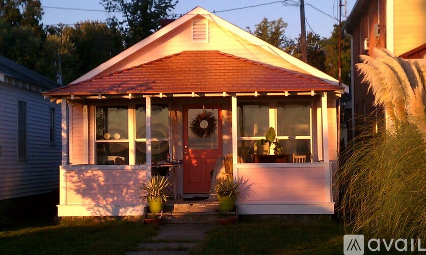A house with a red door and a porch with a wreath on it.