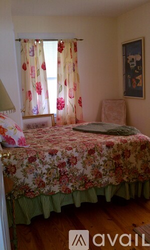 A bedroom with a floral bedspread and a picture on the wall.