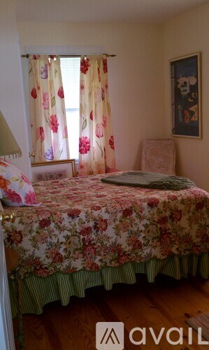 A bedroom with a floral bedspread and a picture on the wall.