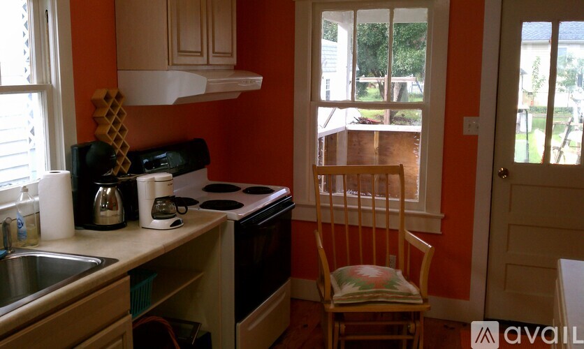 A kitchen with orange walls and a wooden chair.