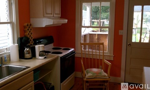 A kitchen with orange walls and a wooden chair.