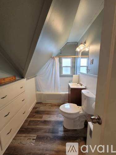 A bathroom with a toilet, sink, and a window.