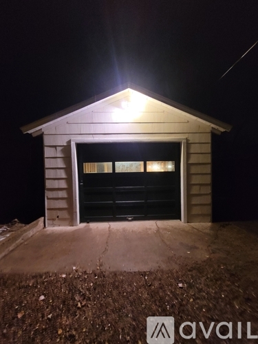 A small building with a lit up roof and a closed black door.