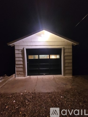 A small building with a lit up roof and a closed black door.
