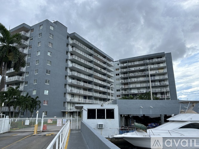 A grey building with a white fence and a boat in front.