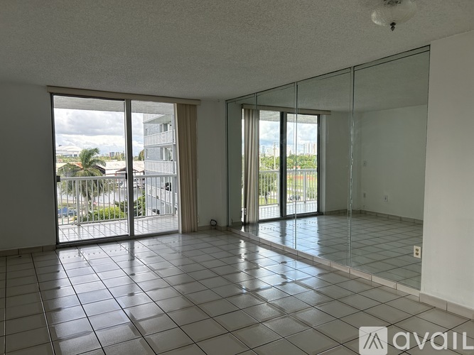 A spacious room with tiled flooring and sliding glass doors leading to a balcony.