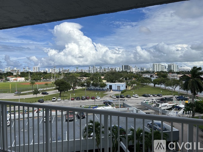 A view from a balcony overlooking a parking lot and buildings.