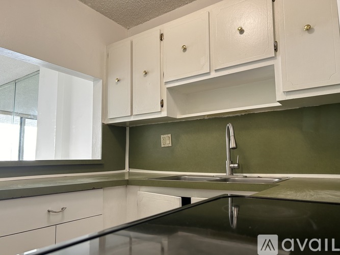 A kitchen with white cabinets and a glass countertop.