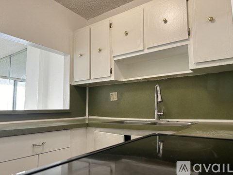 A kitchen with white cabinets and a glass countertop.