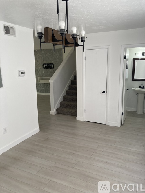 A hallway with a staircase and a chandelier.