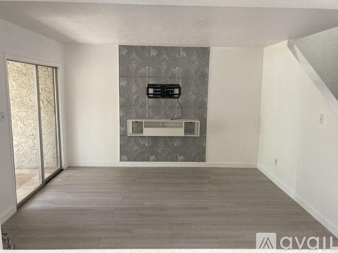 A spacious room with a grey patterned wall and a wooden floor.