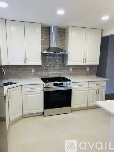 A kitchen with white cabinets and a stove top oven.