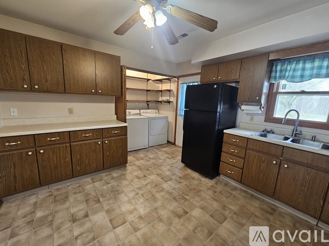 A kitchen with wooden cabinets and a black refrigerator.