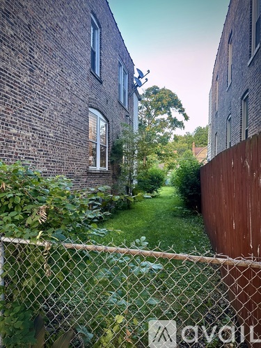 A chain link fence separates a grassy area from a brick building.