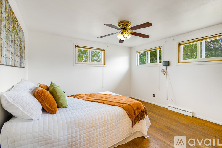 A bedroom with a bed, pillows, and a ceiling fan.