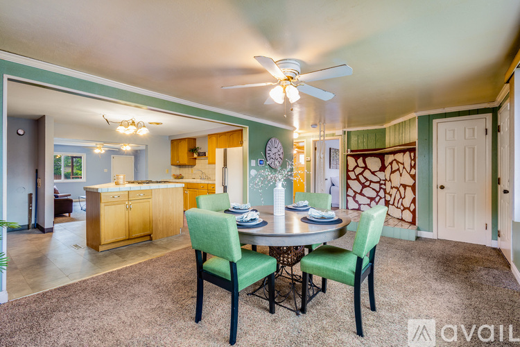 A dining room with a table set for four and chairs around it.