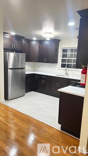 A kitchen with a refrigerator, sink, and cabinets.