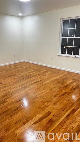 A room with wooden flooring and a window with black bars.
