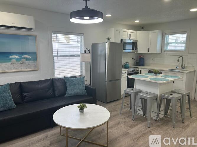 A modern kitchen with a refrigerator, stove, and bar stools.
