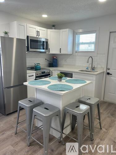 A kitchen with a white countertop and a stainless steel refrigerator.
