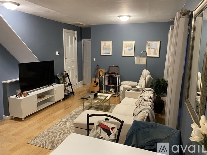 A living room with a television, a guitar, a chair, and a mirror.