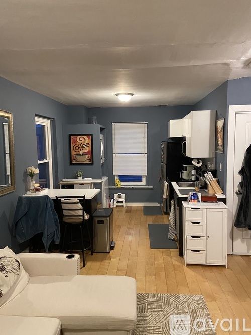 A kitchen with a white fridge and a dining table with chairs.