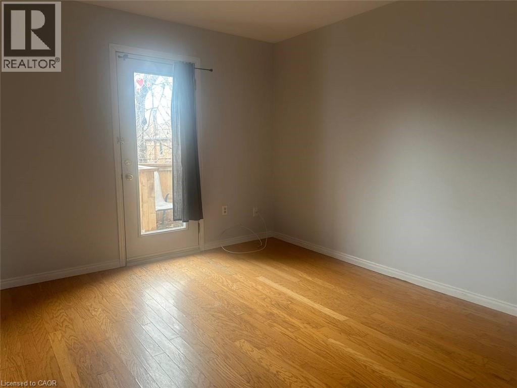 A room with wooden flooring and a door leading to a balcony.