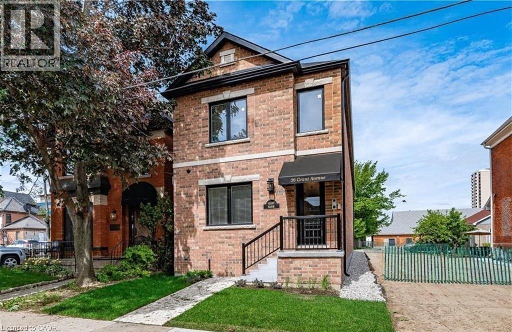 A brick house with a porch and a tree in front.