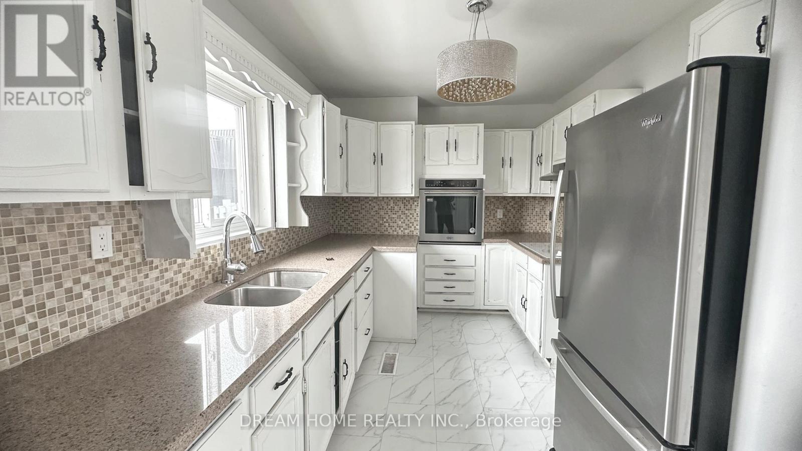 A kitchen with a refrigerator, sink, and cabinets.