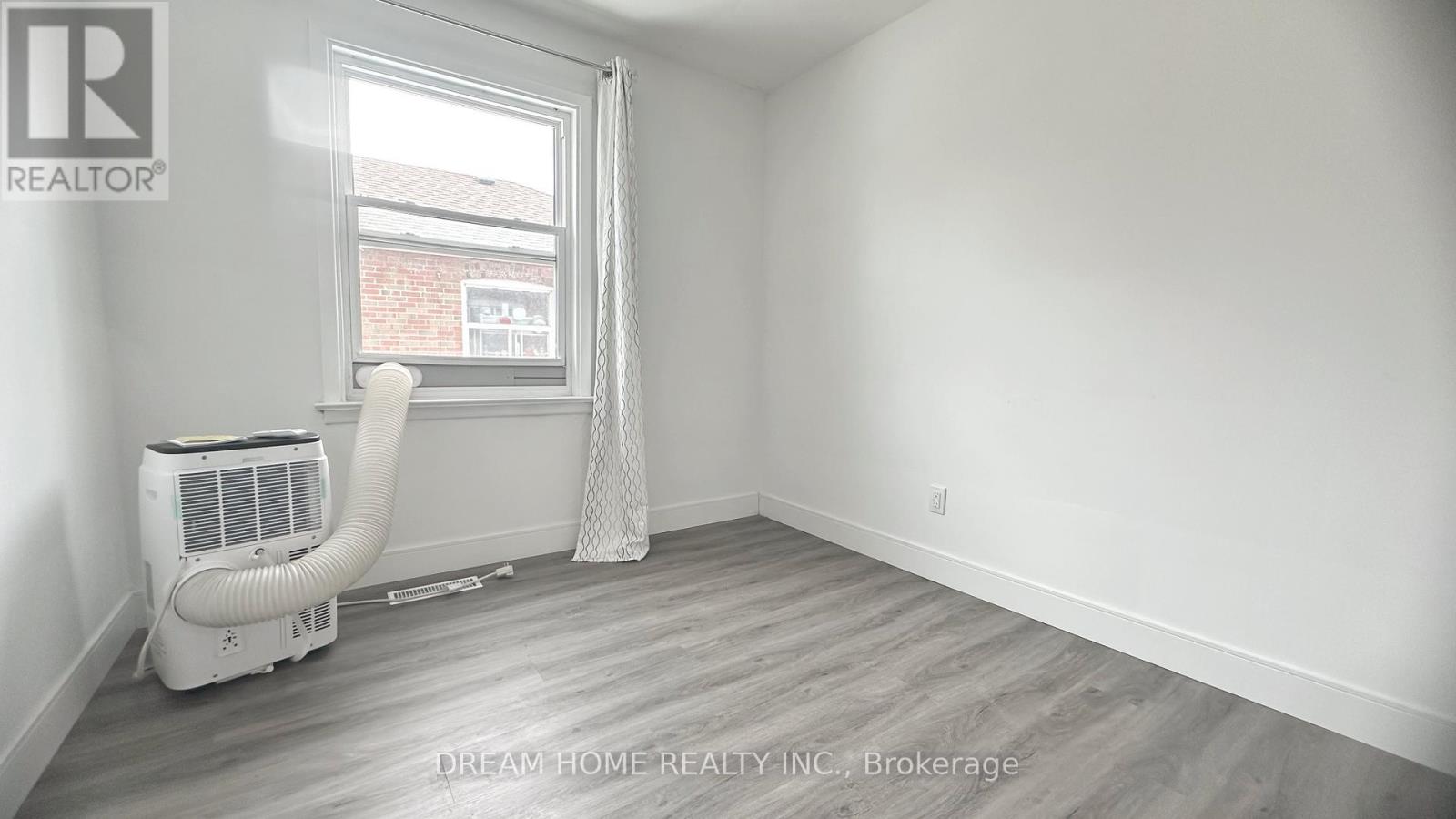 A room with a window, a fan, and a white air conditioner.