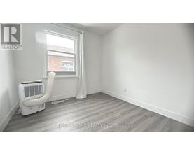 A room with a window, a fan, and a white air conditioner.