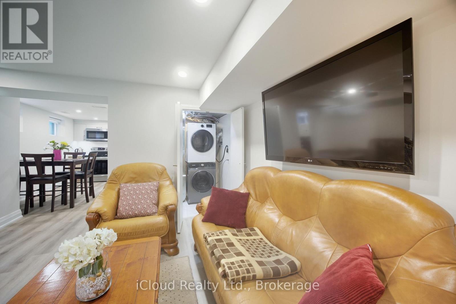 A living room with a brown leather couch and a flat screen TV mounted on the wall.