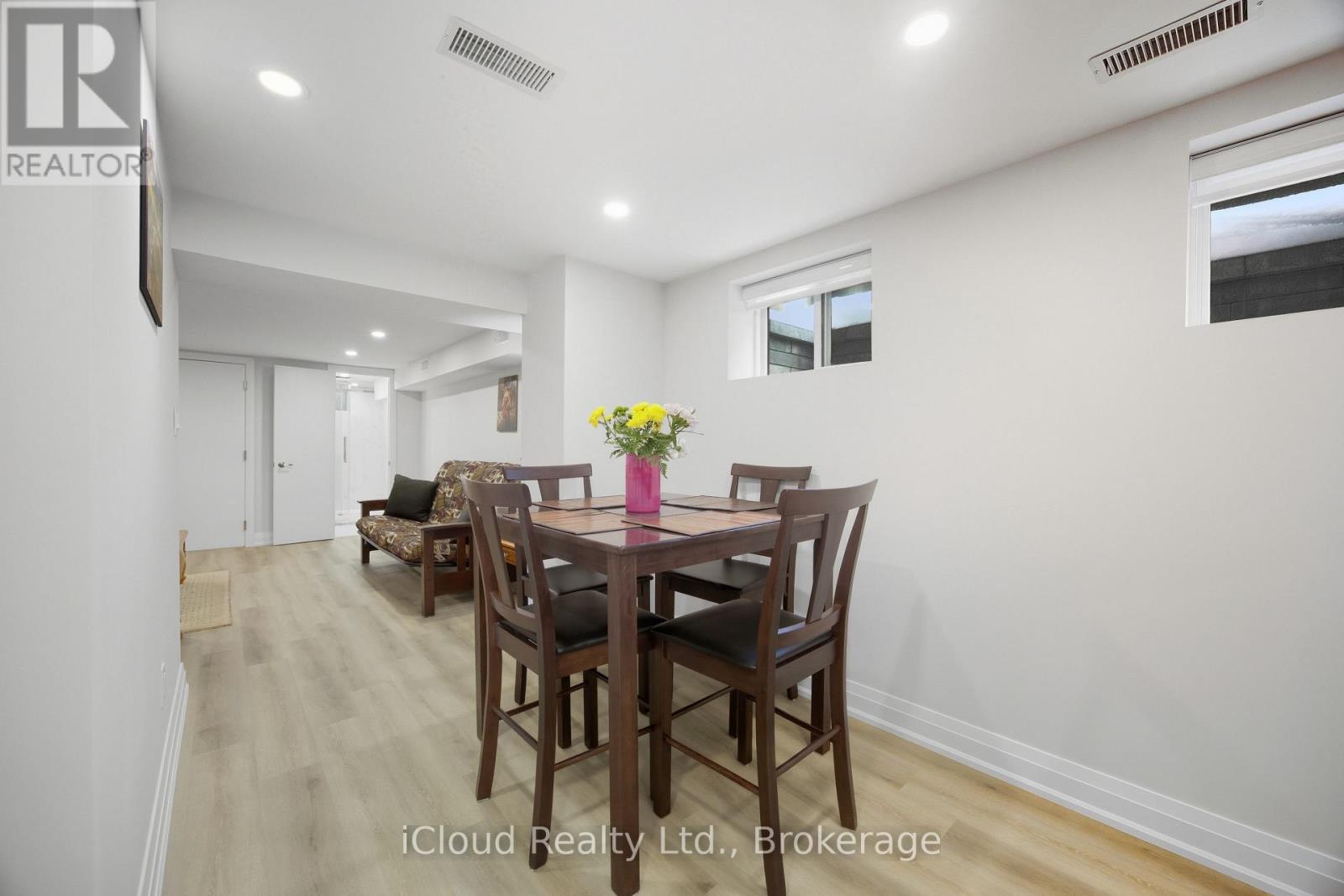A dining room with a table set for two with a vase of flowers on the table.